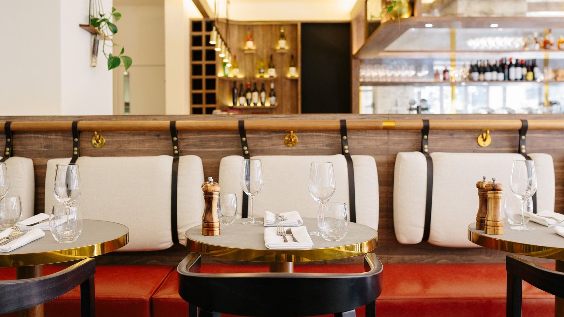 Modern, stylish banquette seating and small round tables set with glasses inside The Croft House at The Sebel Brisbane