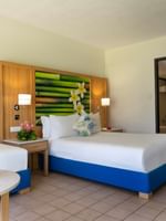 Water bottle on a table by a blue bed base under a tropical bamboo mural in Garden View Room at The Naviti Resort - Fiji