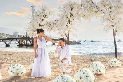 Couple celebrating beach wedding ceremony with white floral decorations and ocean view at Playa Los Arcos Puerto Vallarta