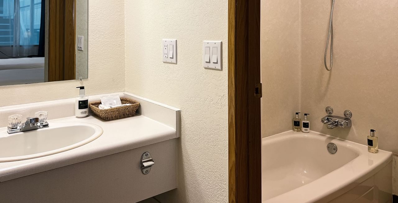 Hotel bathroom with bathtub, sink, soap, and towels
