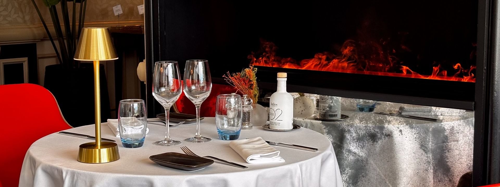 Round dining table with red chairs by a modern fireplace in Téséo at Warwick Geneva