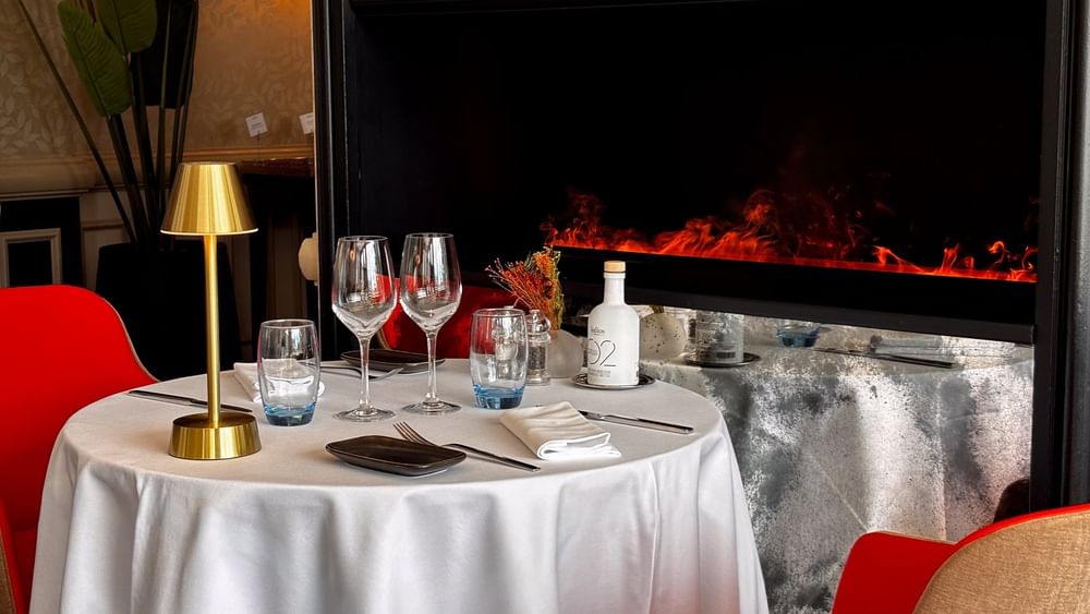 Round dining table with red chairs by a modern fireplace in Téséo at Warwick Geneva