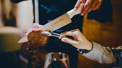 A chef cutting meat while a man holding at Vasa Hotel Surabaya