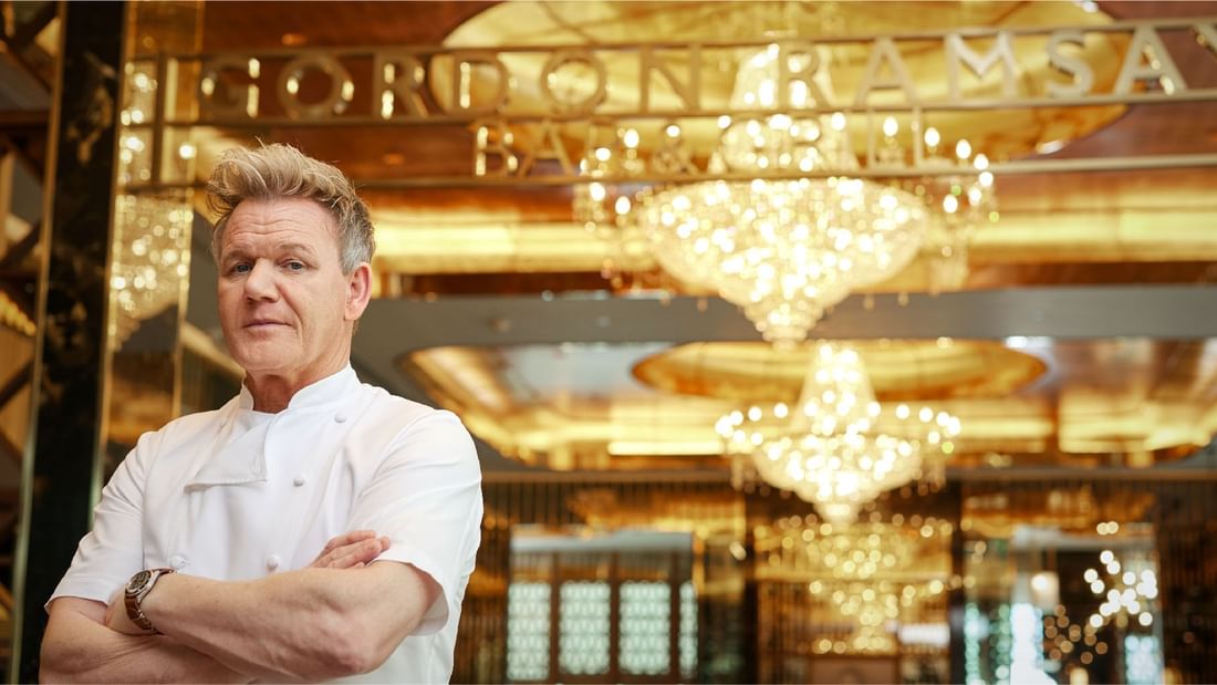 Chef Gordon Ramsay stands with arms crossed in his chef’s coat, against the glamorous backdrop at Sunway Resort