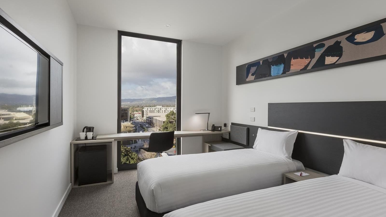 TV facing two beds and workspace by the window in Superior Room Two Single Beds City View at Ibis Adelaide