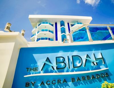 Hotel facade with blue signage at The Abidah Hotel, a boutique adults-only hotel in Barbados with pool and bar