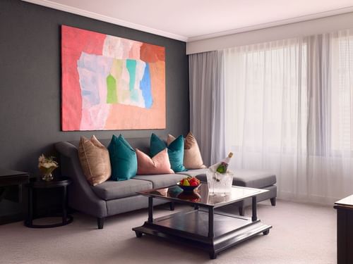 Living area with a colorful abstract painting, and sofa with beige cushions in Signature Suite at Sofitel Brisbane Central