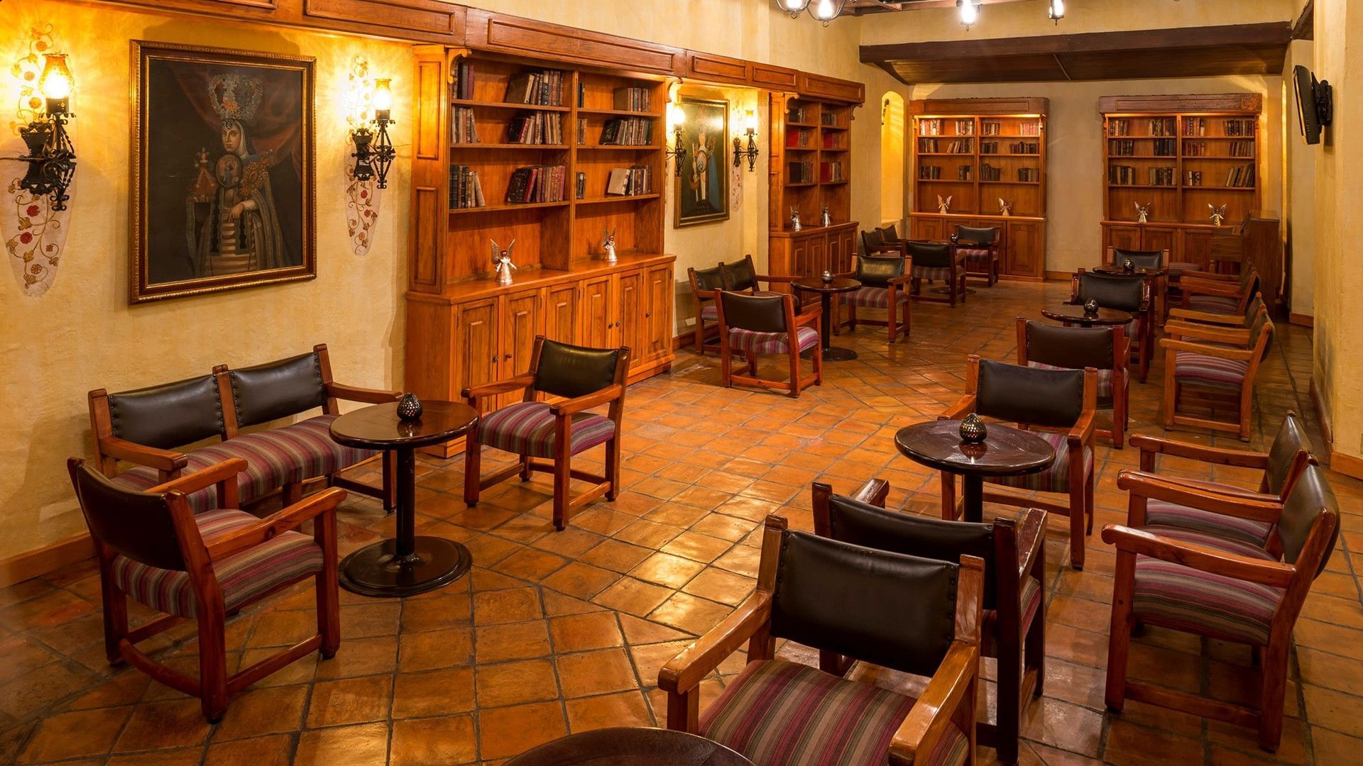 Bar Las Novicias with warm lighting, wooden bookshelves, and terracotta floors at Quinta Real Oaxaca