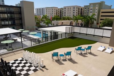 Rooftop terrace with a large chess set, lounge chairs, and a pool in the back at The Harrison Hotel Downtown Hollywood