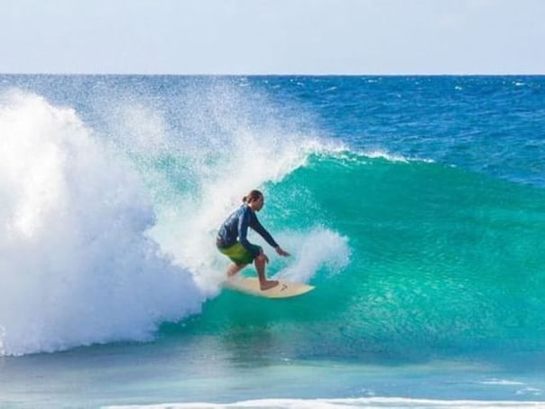 Man surfing on a high tide on a sunny day near Paradise Bay Resort