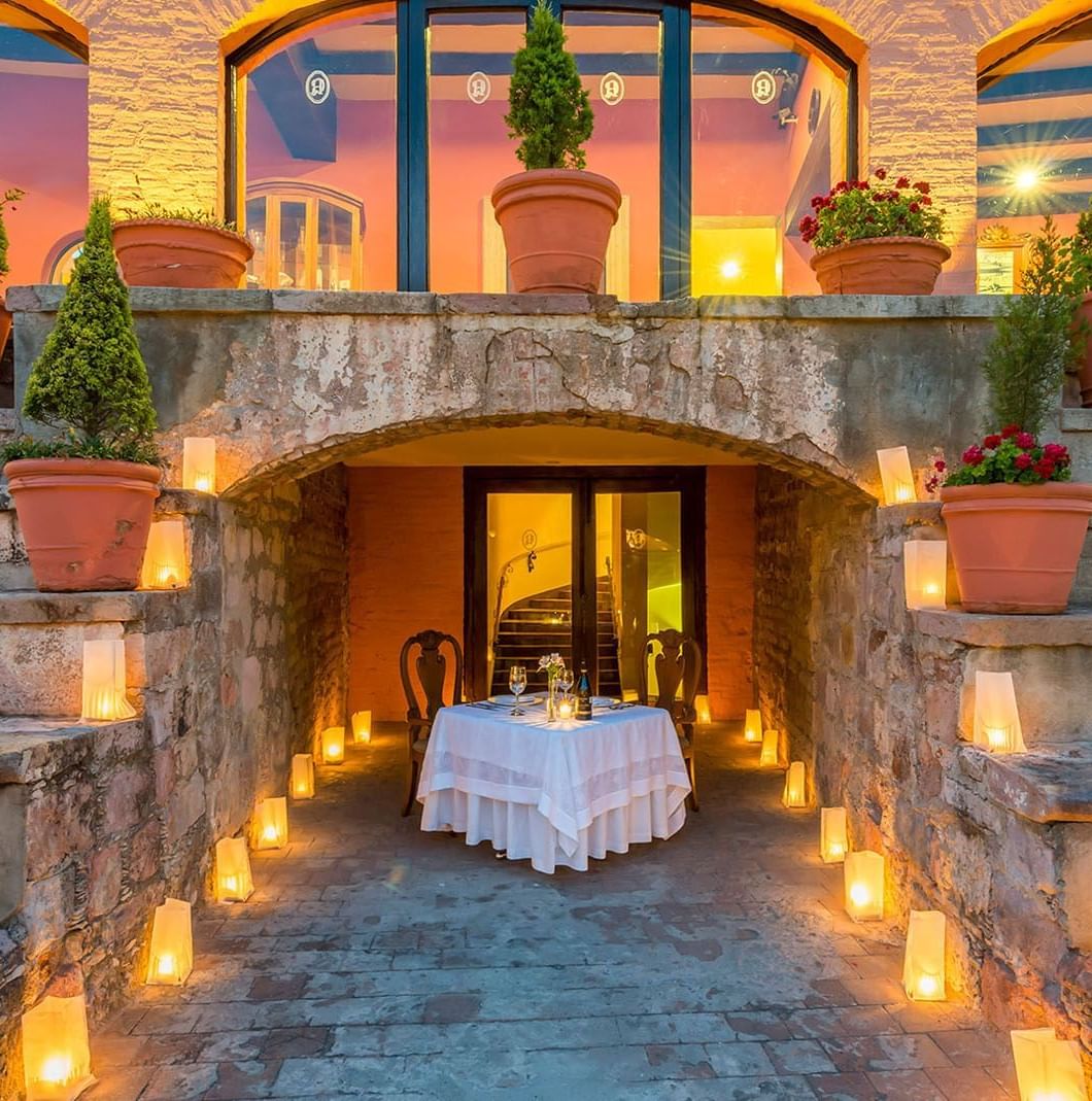 Private table for two framed by a stone arch and glowing candles in the courtyard at Quinta Real Zacatecas