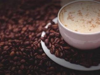 A cup of coffee surrounded by coffee beans at Artmore Hotel