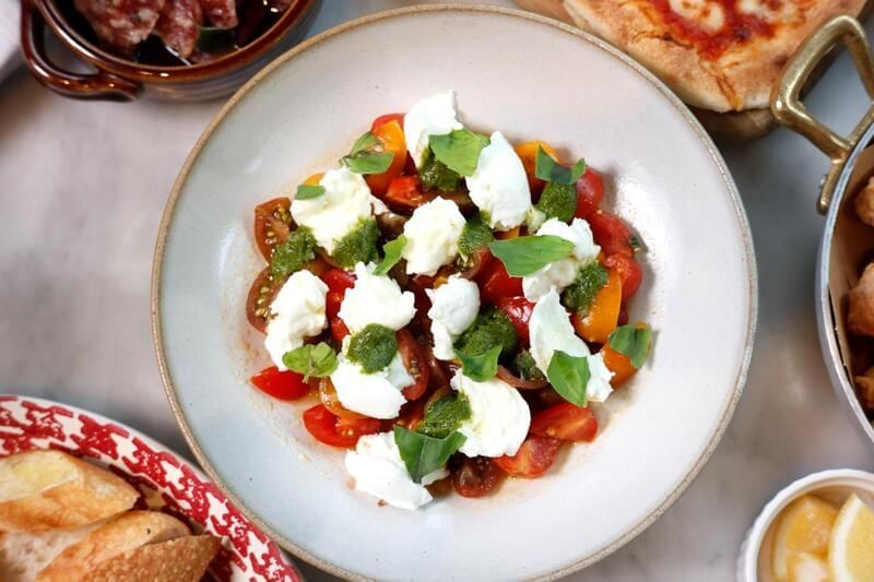 Fresh salad with cherry tomatoes, creamy mozzarella, and pesto served at the family dinner in Park Hyatt Saigon