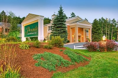 The entrance sign and building of The Pointe at Castle Hill on a lush landscaped hillside