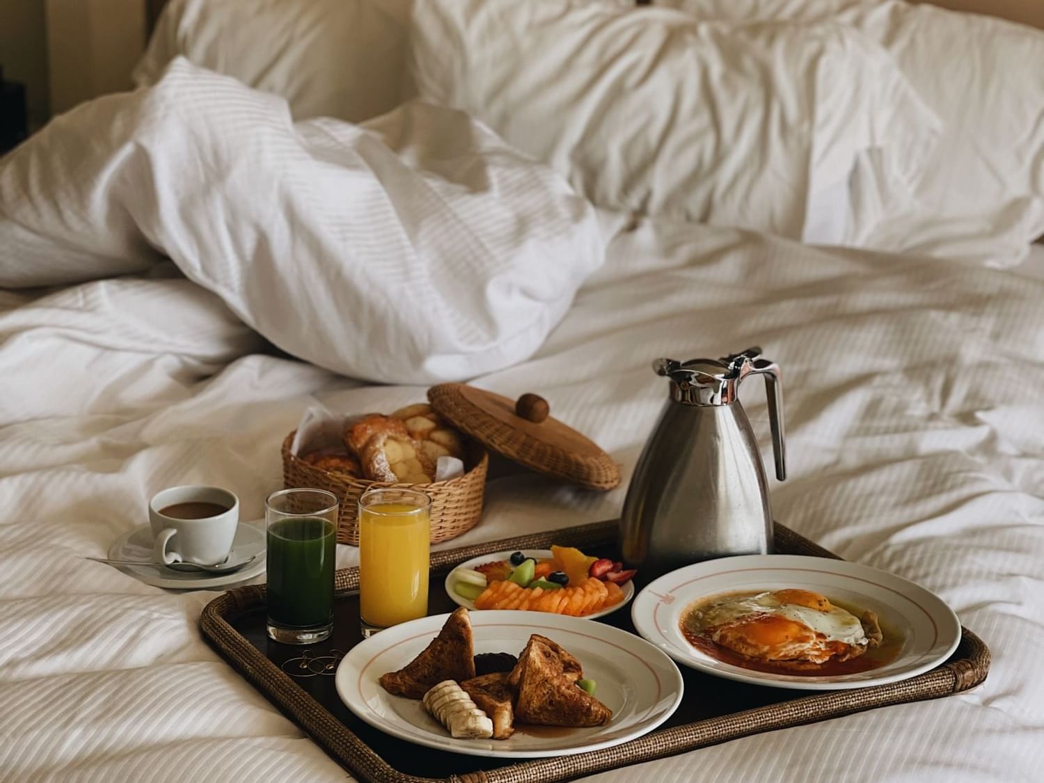 Primer plano de un desayuno continental en una cama en Los Cabos