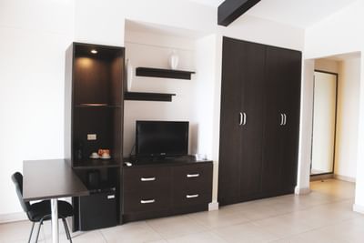 Interior de habitación con muebles de madera oscura, un mueble de habitación para TV y un área de comedor pequeña en el hotel The Beach House de Panamá