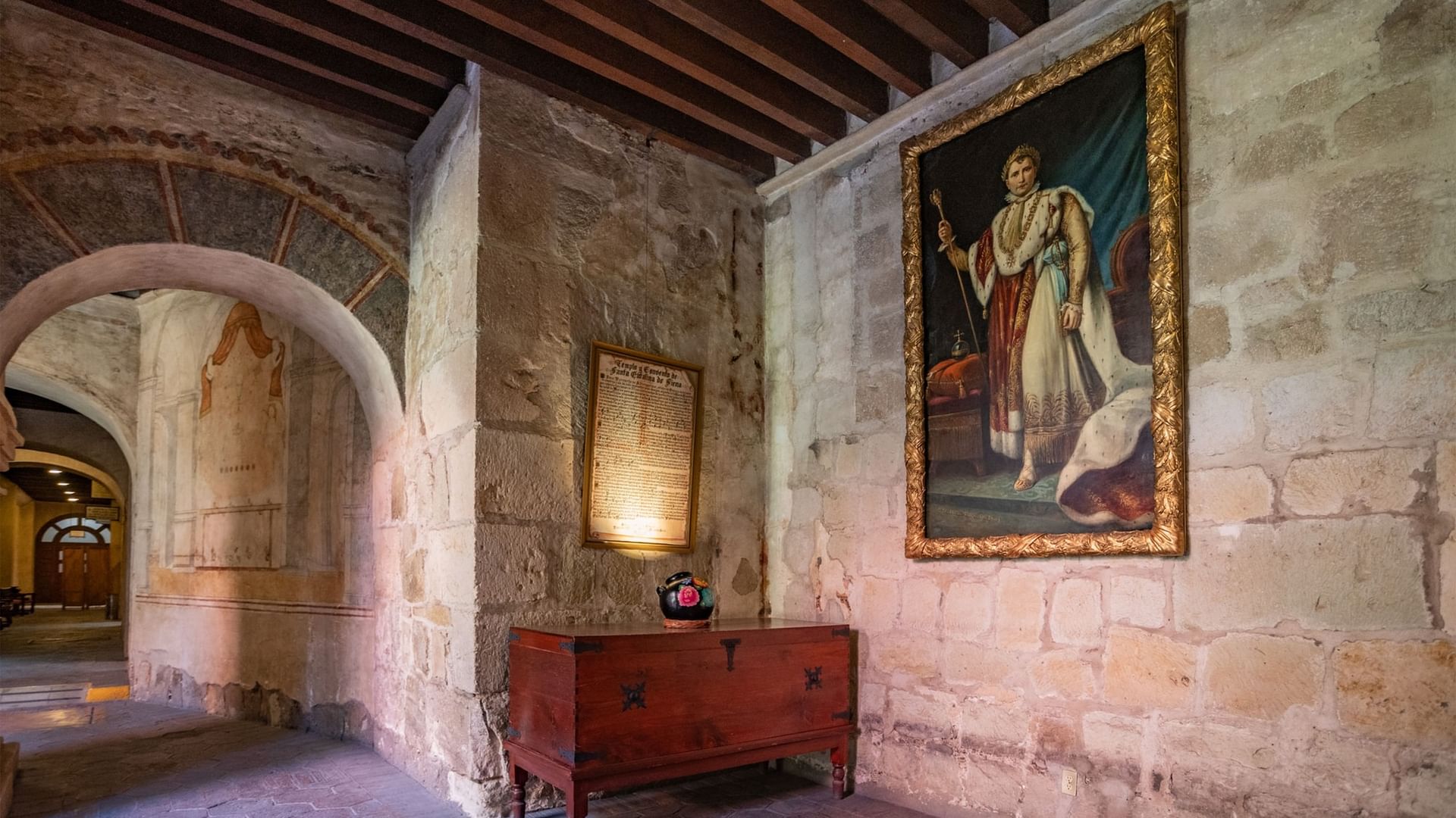 Habitación histórica con pintura de Napoleón, muros de piedra y cofre de madera en Quinta Real Oaxaca