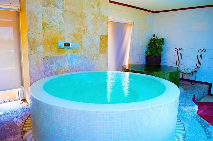 Circular plunge pool under a waterfall feature by a green tiled tub in Chakra Spa at Accra Beach Hotel