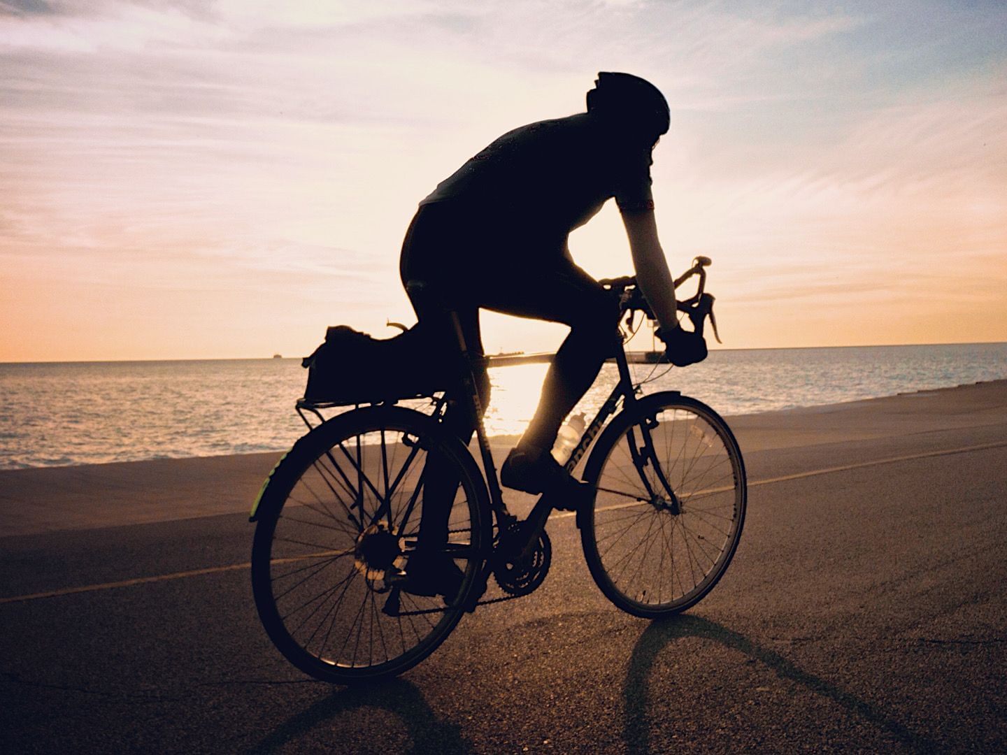 A guy riding a cycle in Falmouth Beach near Falmouth Tides