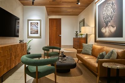 Casa Cielo living area with green chairs, tan sofa, and warm decor, creating a stylish look at Singular Signature Residences