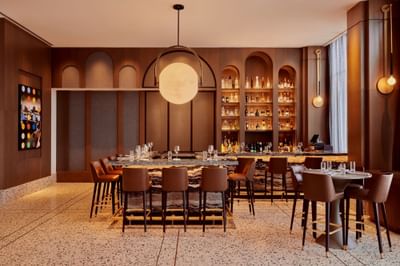 Sleek bar area with dining table set up in Lobby Bar at Godfrey Hotel Detroit