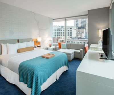 Bed, sofa & a TV in Accessible King Room at Kinzie Hotel