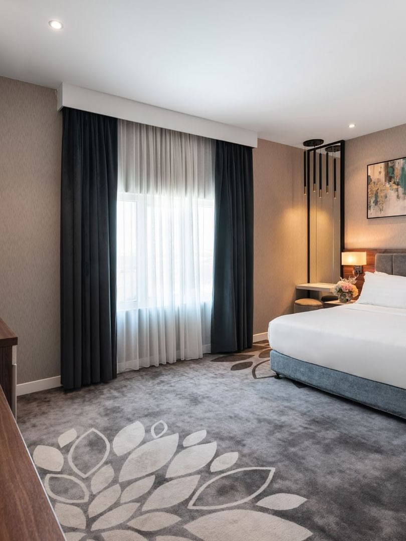 Large bed with a dark wooden dresser and a large mirror in Family Suite Sea View at Warwick Al Jubail