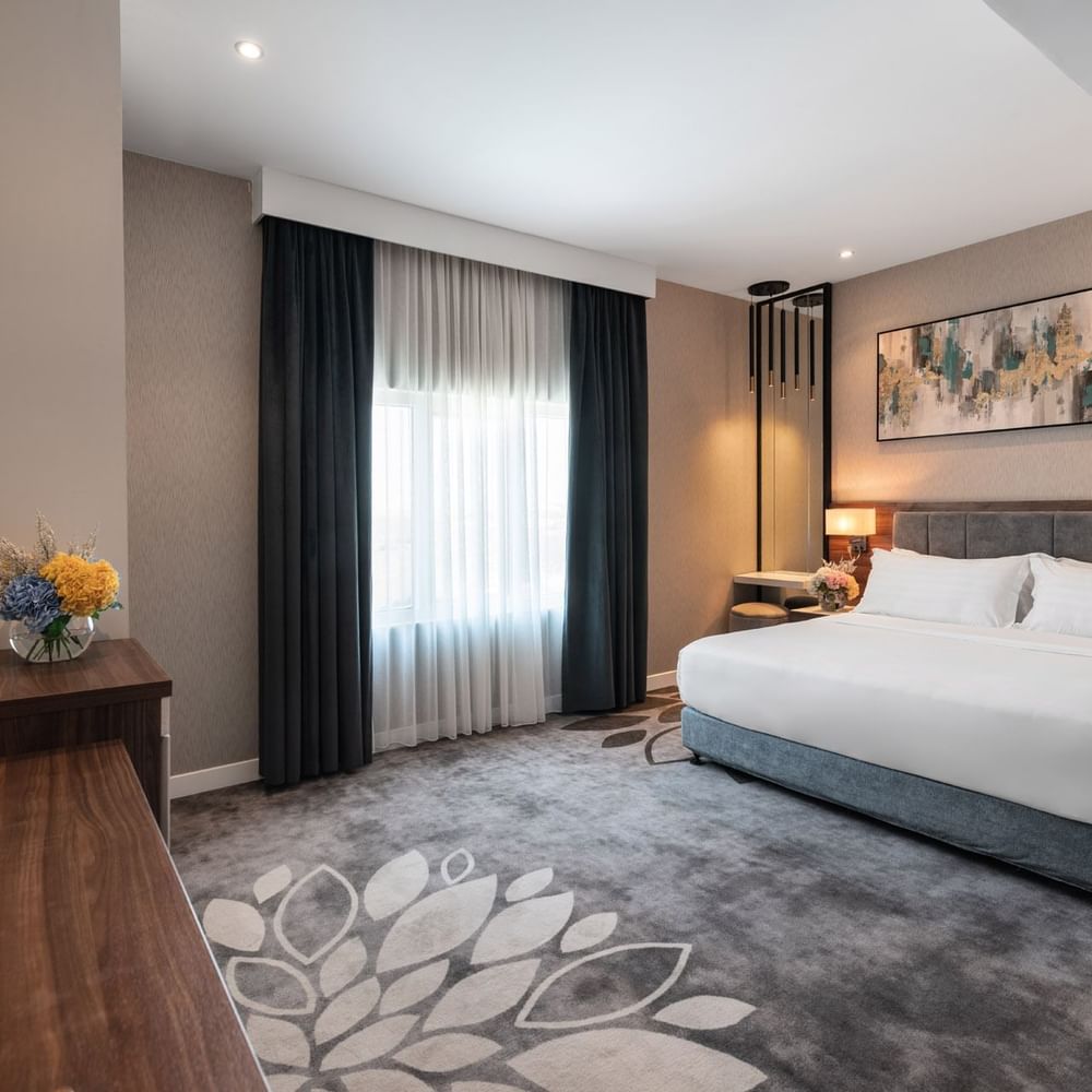 Large bed with a dark wooden dresser and a large mirror in Family Suite Sea View at Warwick Al Jubail