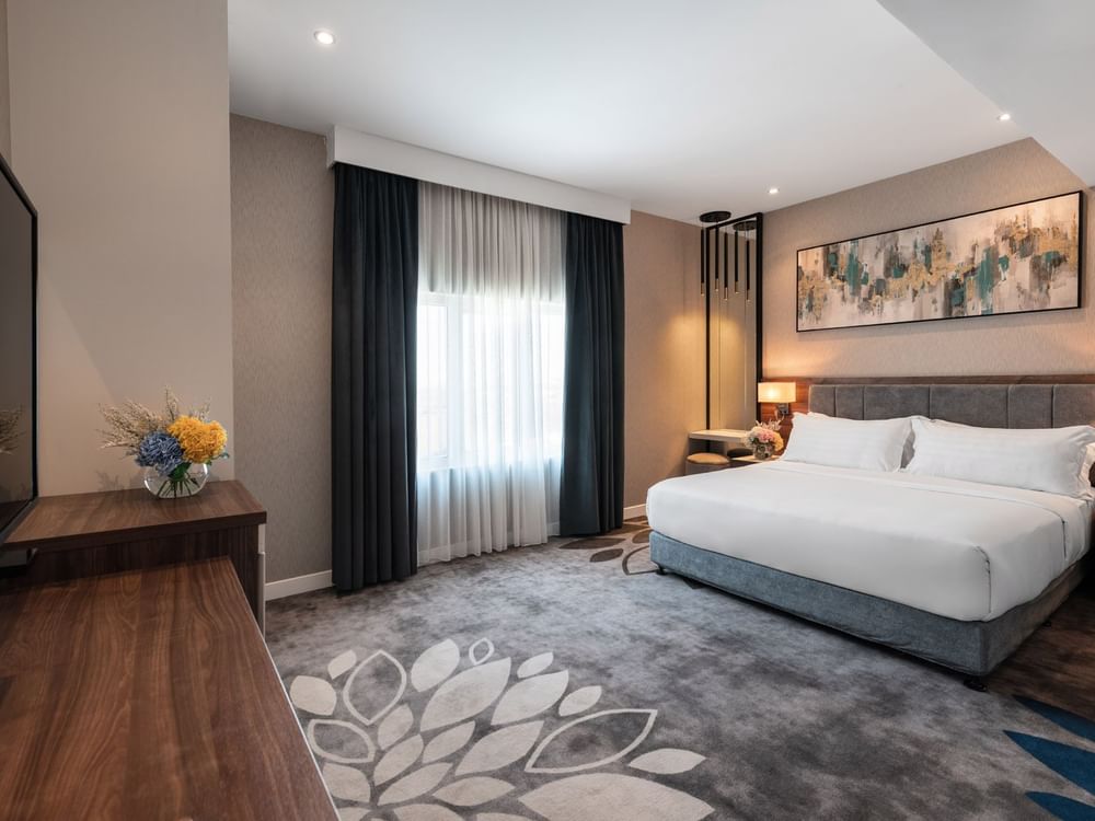Large bed with a dark wooden dresser and a large mirror in Family Suite Sea View at Warwick Al Jubail