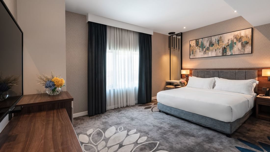Large bed with a dark wooden dresser and a large mirror in Family Suite Sea View at Warwick Al Jubail