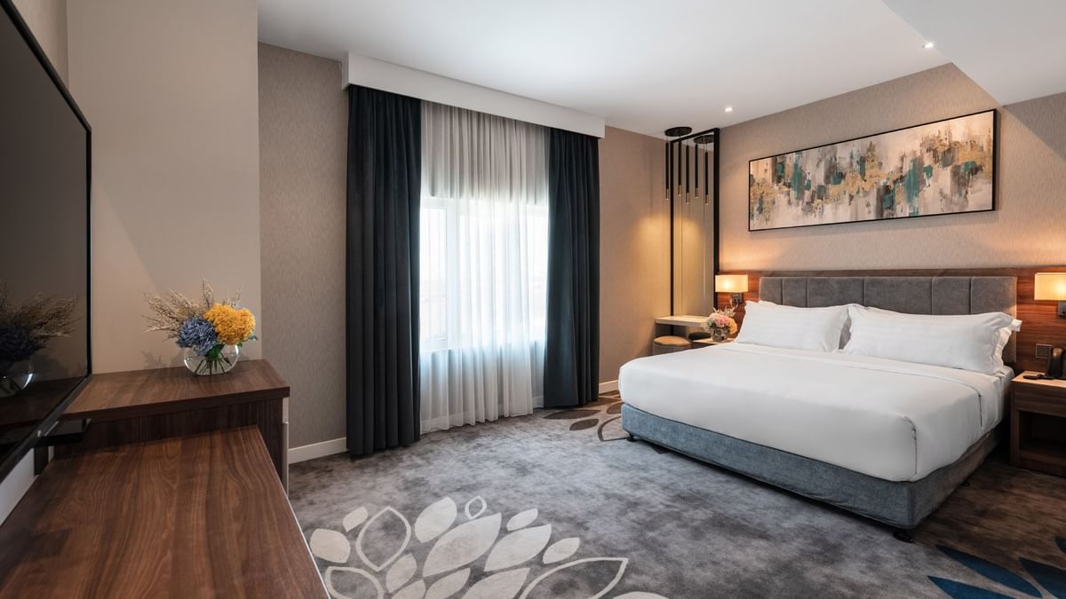 Large bed with a dark wooden dresser and a large mirror in Family Suite Sea View at Warwick Al Jubail