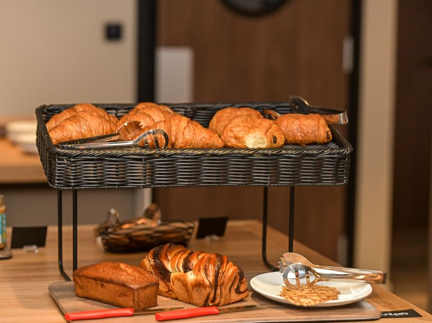Étal de croissants et pains variés sur un plateau en bois à l'Hôtel Rivella.