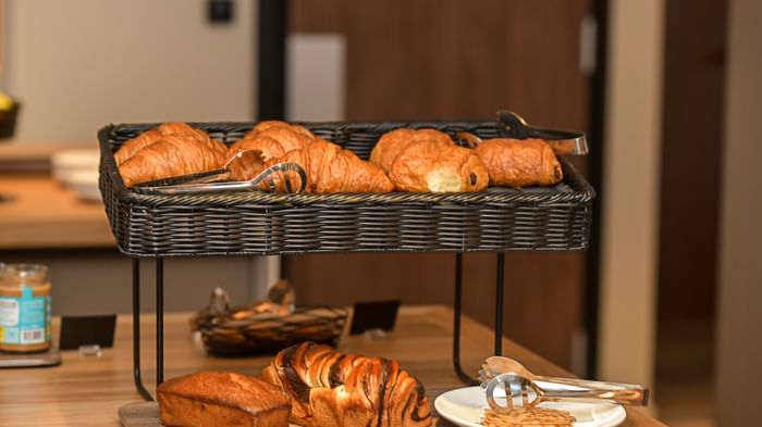 Étal de croissants et pains variés sur un plateau en bois à l'Hôtel Rivella.