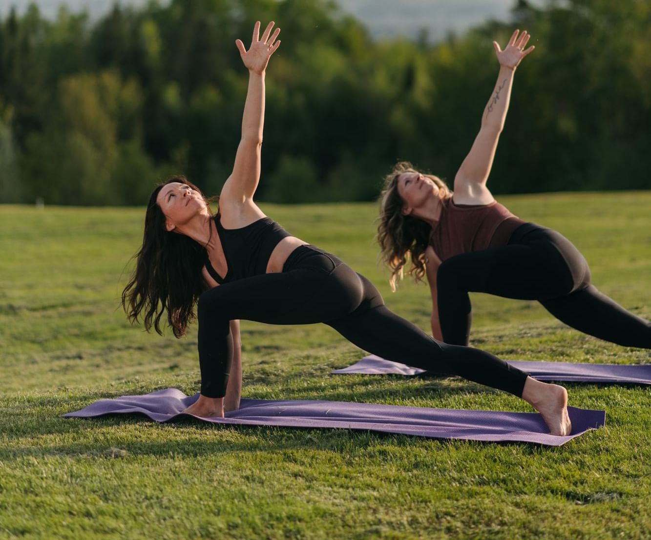 Two women doing an extended side angle pose on a green lawn outdoors at Mountain View Grand Resort & Spa