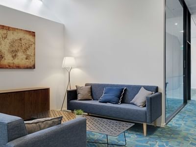 Modern lounge area with blue sofas, world map artwork, and floor lamp at UniLodge Auckland Central
