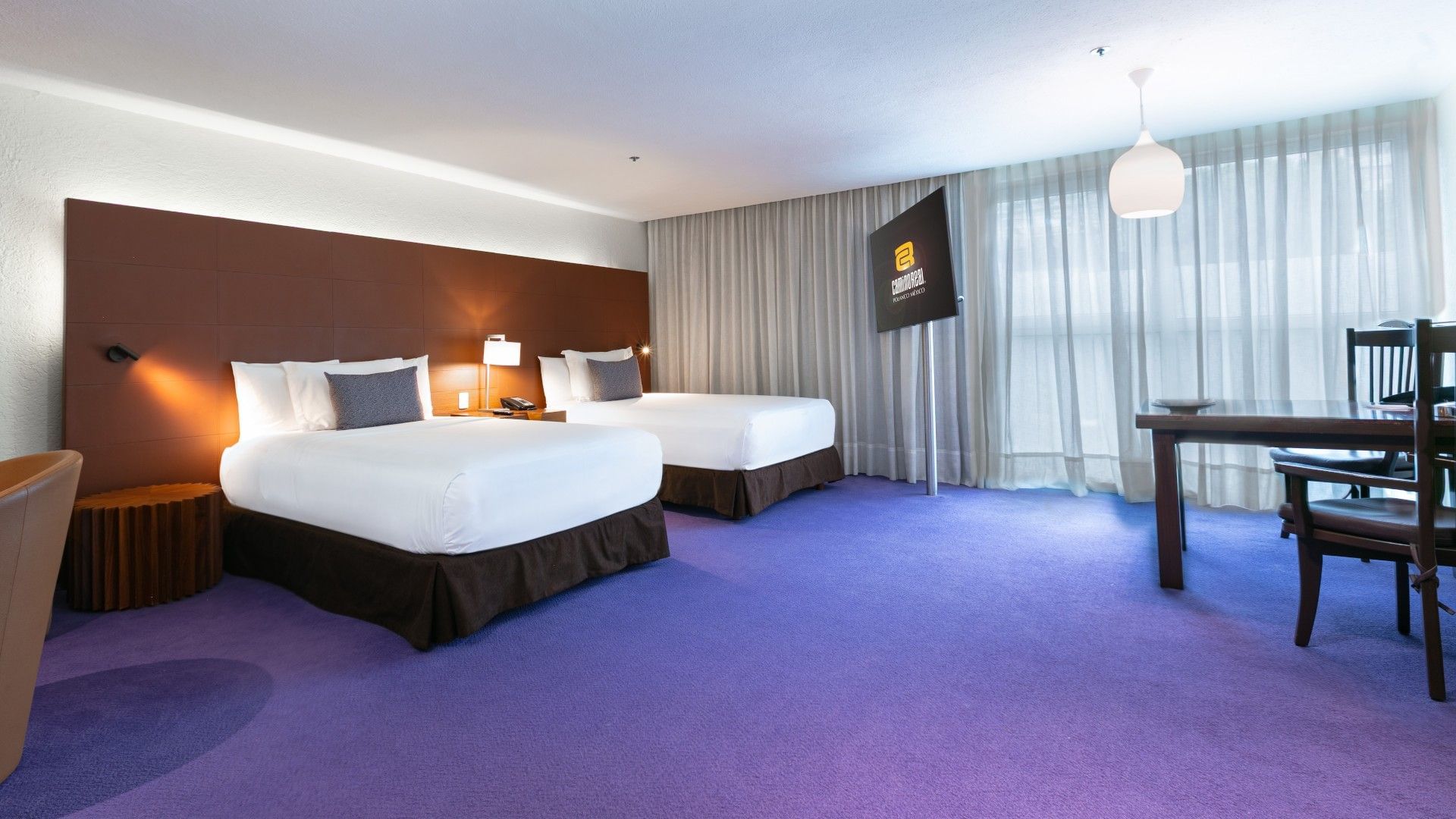 2 Double Junior Suite with twin beds, purple carpet, and a TV on a rotating stand at Camino Real Polanco Mexico