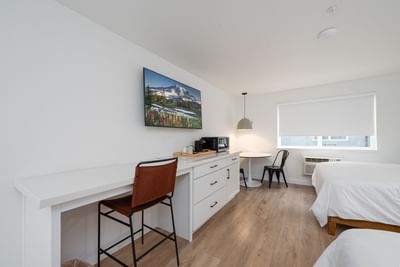 Workspace, white cabinet, and microwave facing the cozy beds in the Double Queen Room at The Varsity North