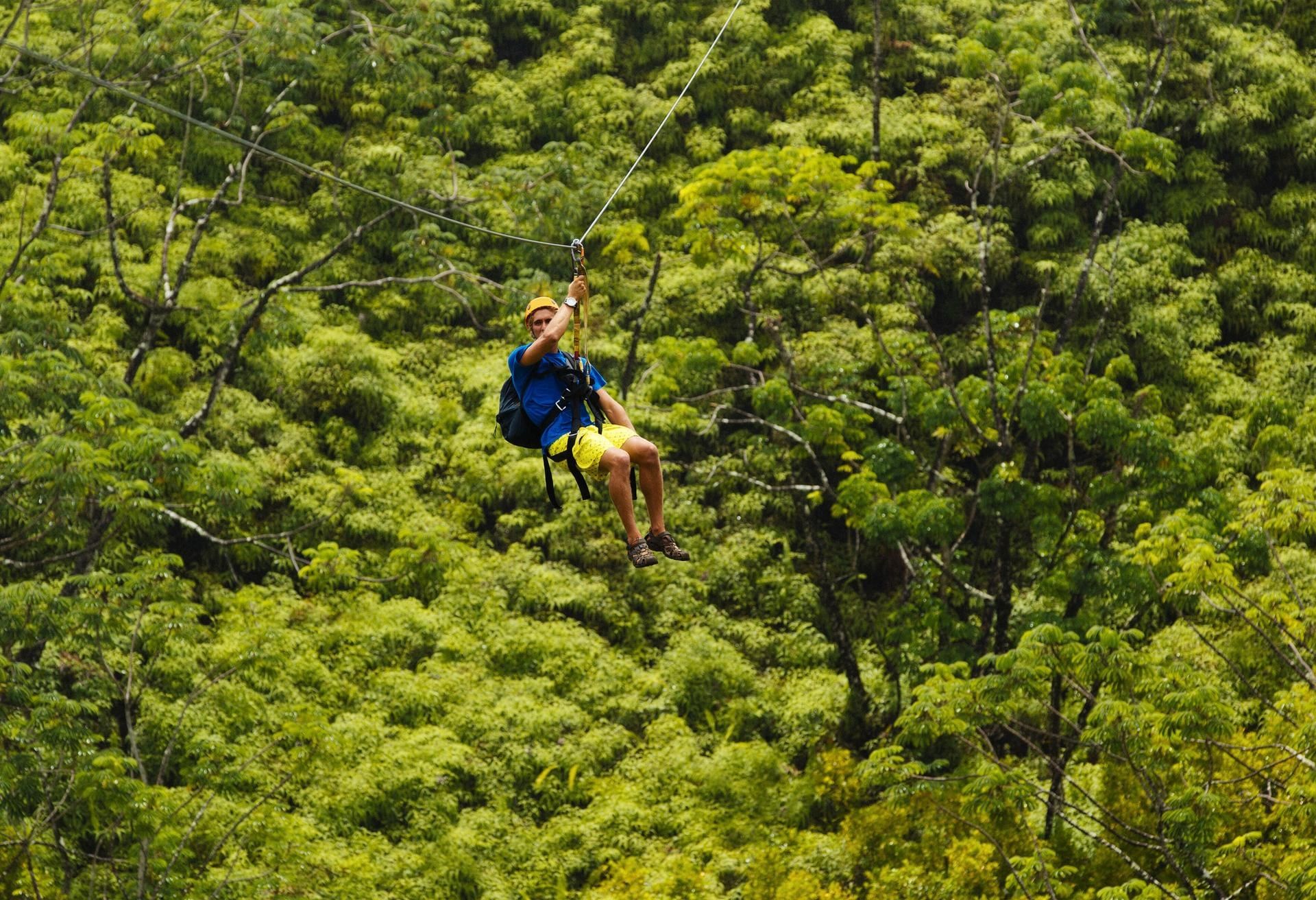 An adventurous male guest zip-lines over the vast tropical Mayan jungle near the stunning La Zebra Hotel