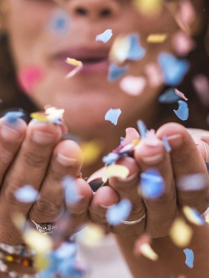 Close-up of a person blowing colorful confetti from their hands at Le Grand Hôtel des Thermes