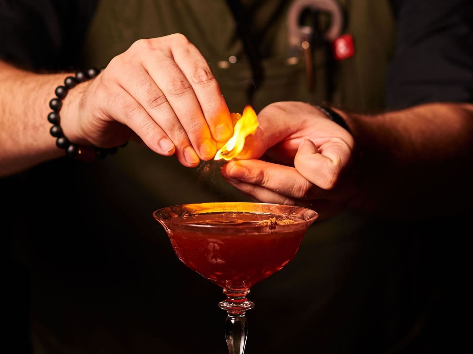 bartender placing garnish on fire on top of cocktail