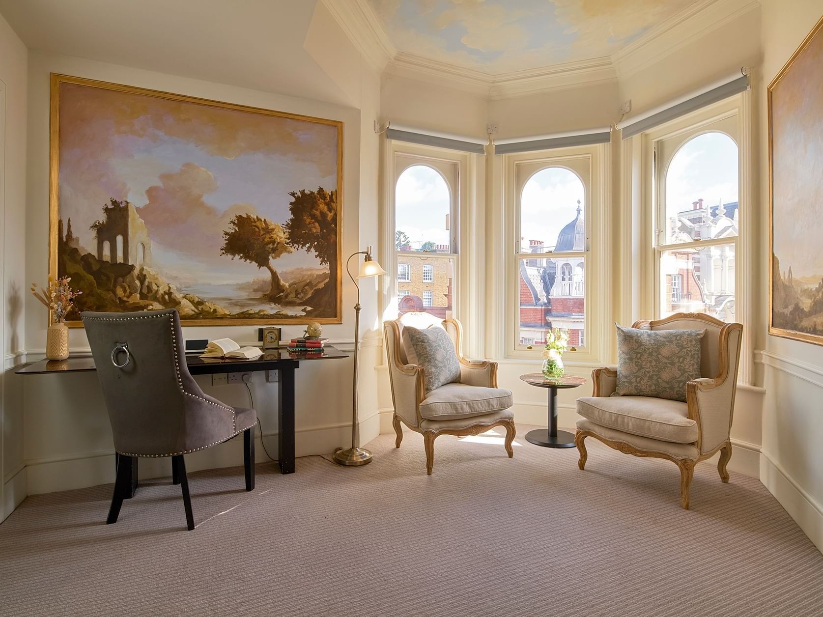 Spacious Junior Suite with bay windows, classic armchairs, writing desk, and London city views at Sloane Square Hotel.
