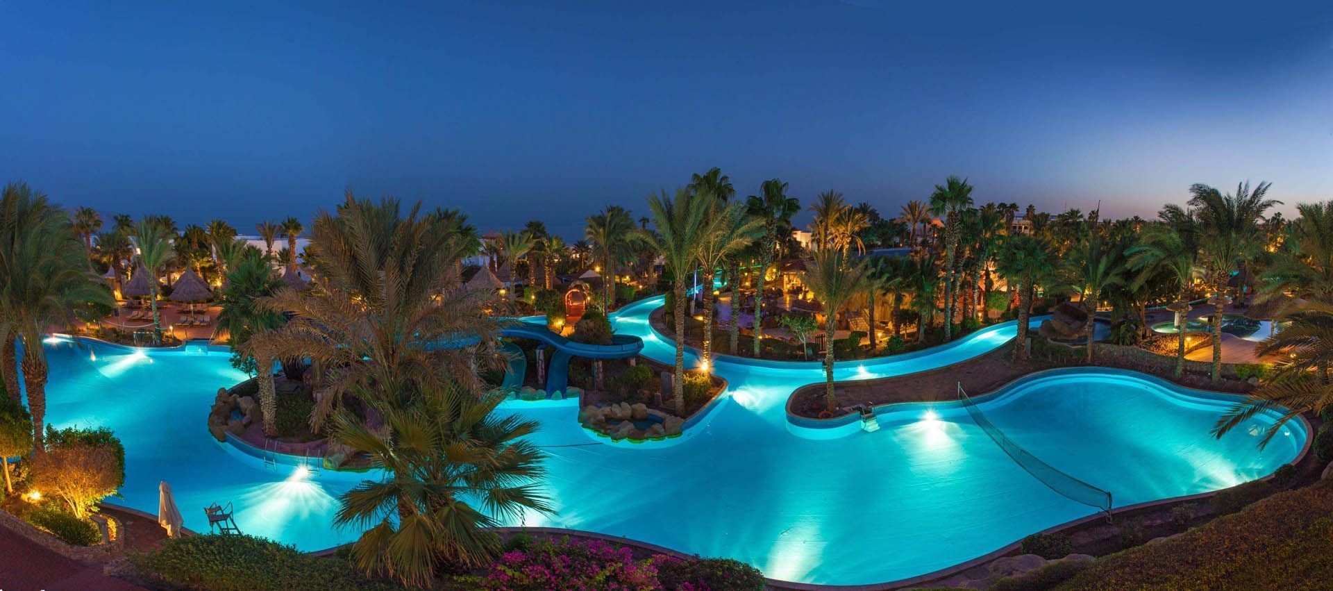 Serene evening view of Pickalbatros Golf Beach Resort pool with palm trees against a twilight sky by Beach Sharm El Sheikh