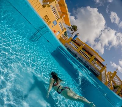 Woman swimming in the pool under a clear blue sky at Amsterdam Manor Beach Resort