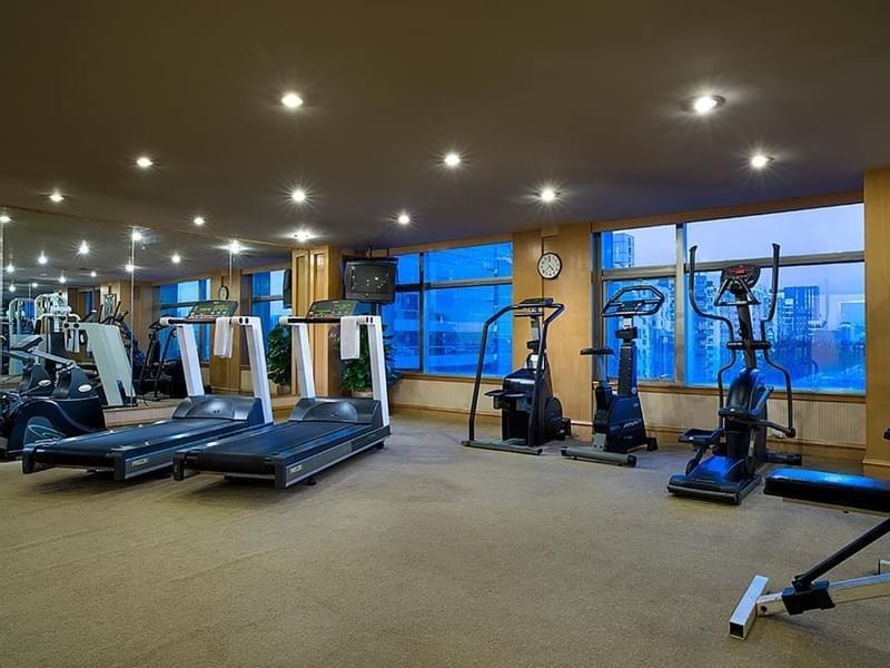 Gym with treadmills, elliptical machines near large windows with city views at Celebrity International Grand Hotel