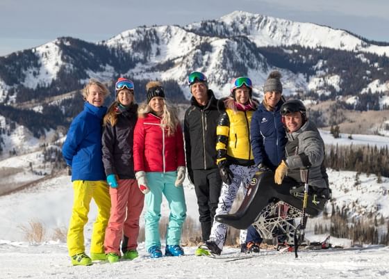 Group of people in front of a mountain range posing for a photo near Stein Eriksen