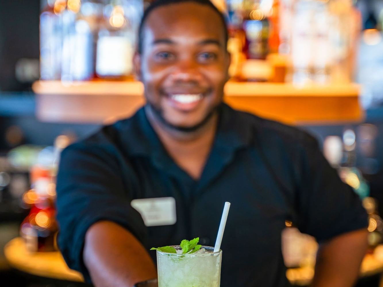 Bartender presenting a refreshing cocktail garnished with mint in the Breeze Restaurant at Golden Rock Resort