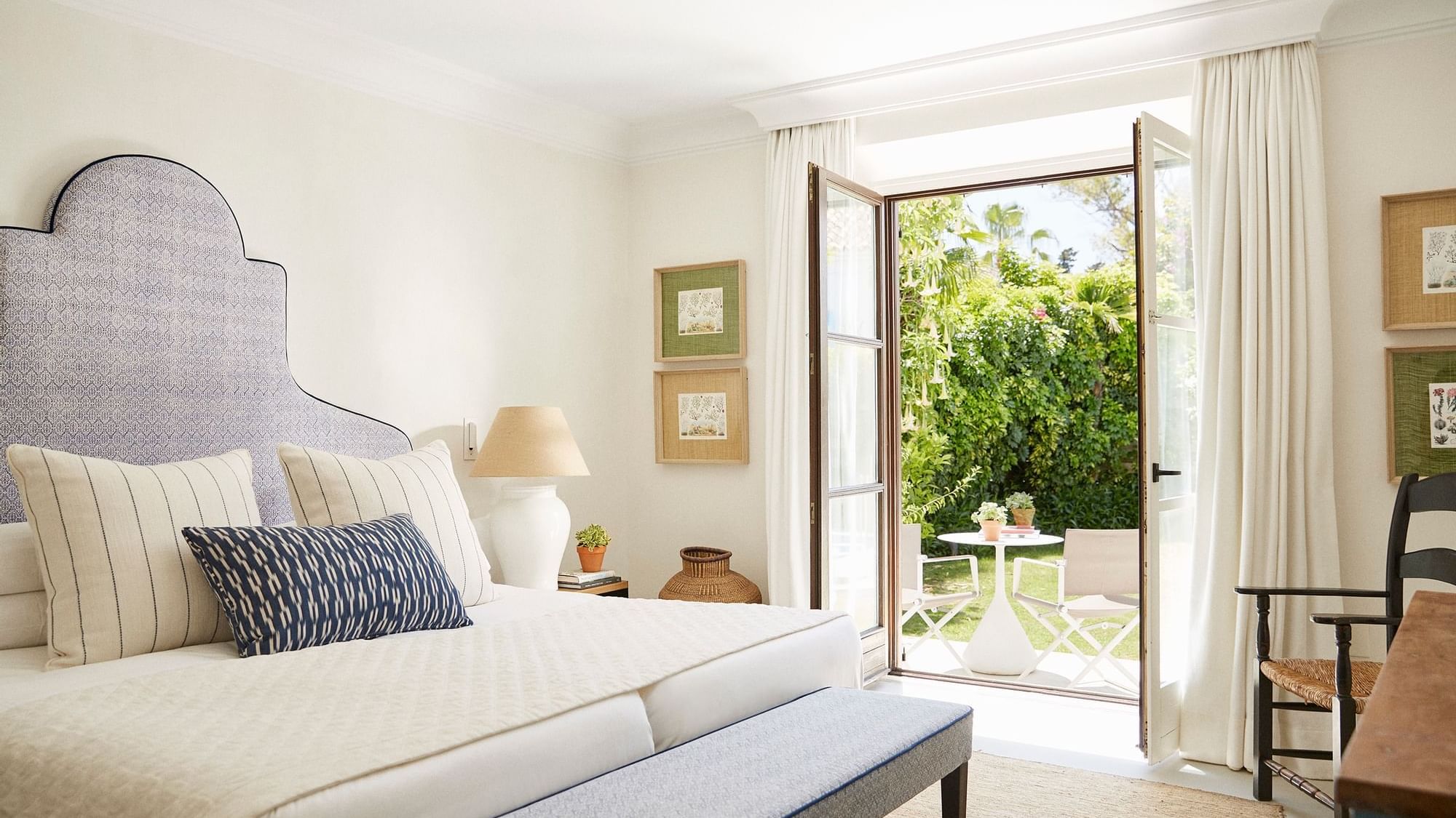 Three-bedroom villa with a bench at the foot of the bed facing a lush patio at Marbella Club