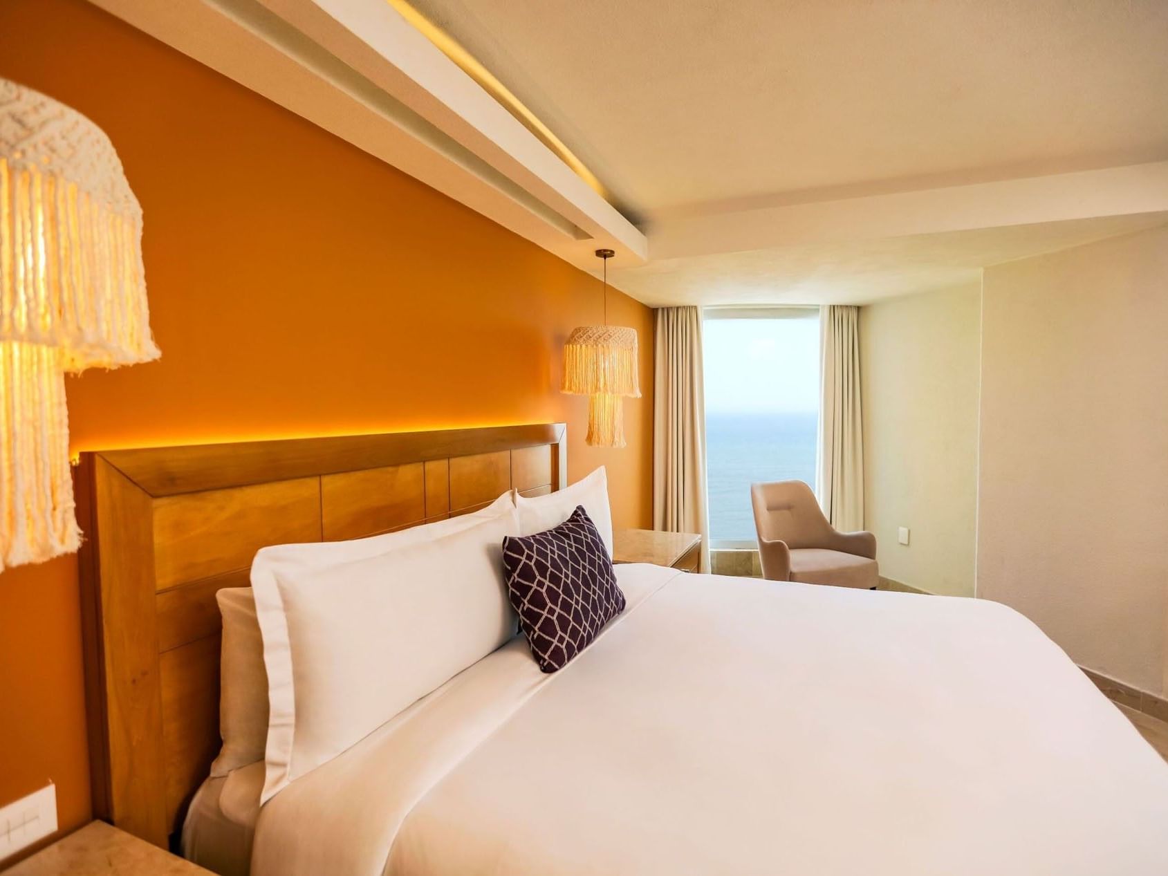 King Camino Real Club with orange accent walls and stylish macramé hanging lamps at Camino Real Veracruz