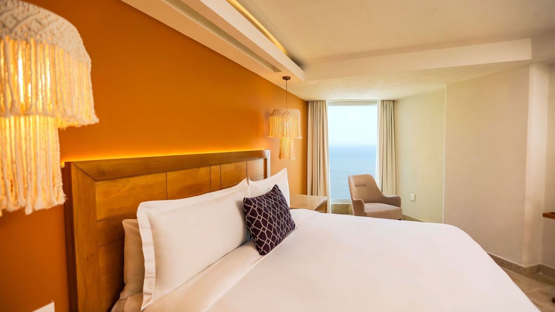 King Camino Real Club with orange accent walls and stylish macramé hanging lamps at Camino Real Veracruz