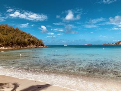 Clear turquoise bay water and a rocky green hillside under a bright blue sky at the scenic Emerald Beach Resort
